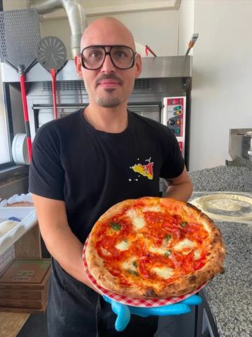 Pizza alla diavola appena sfornata, in mano al pizzaiolo